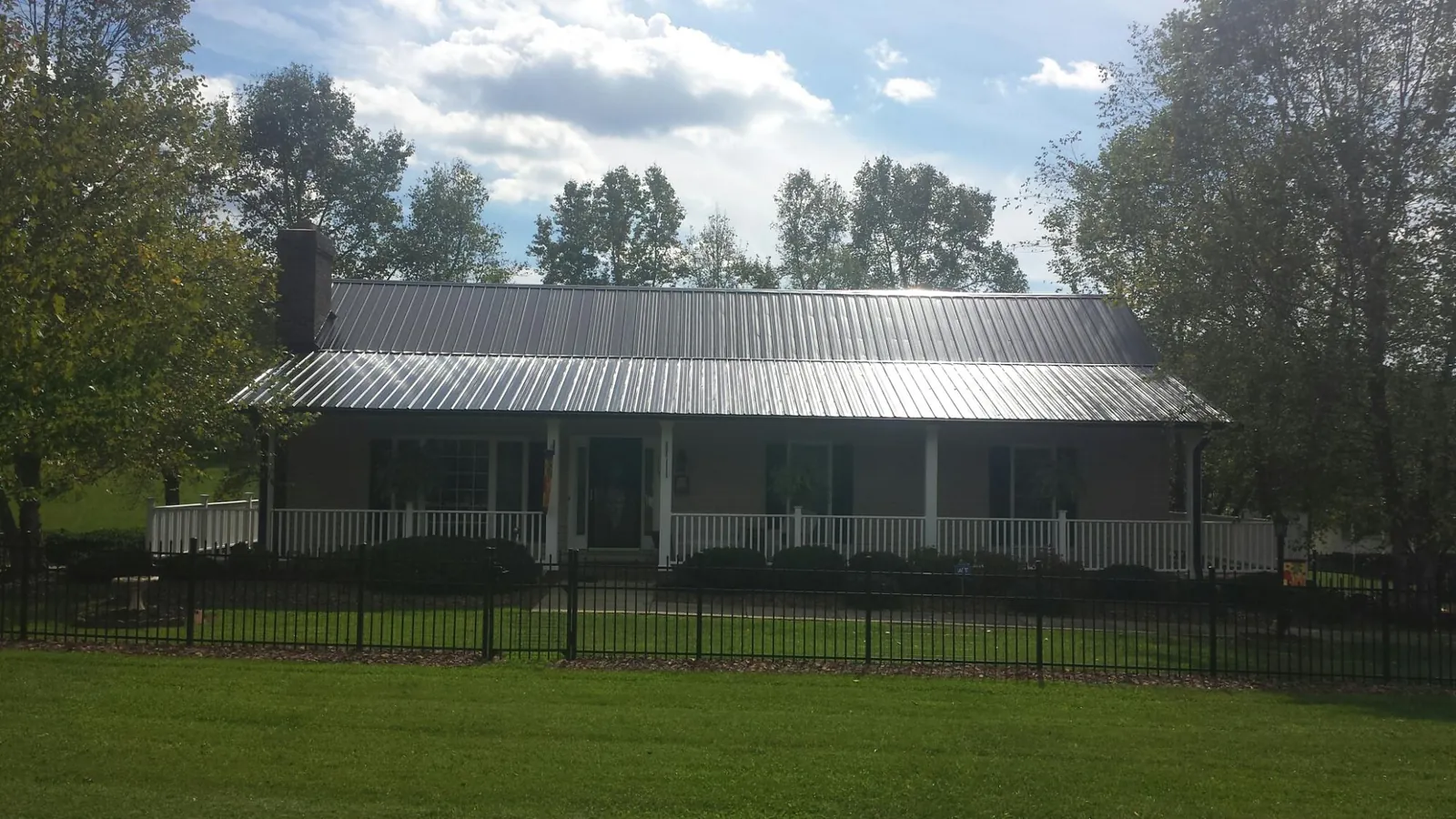 Gray metal roof on a brick ranch with a full width front porch — Gutter Guard Installation work by our crew in Intervale
