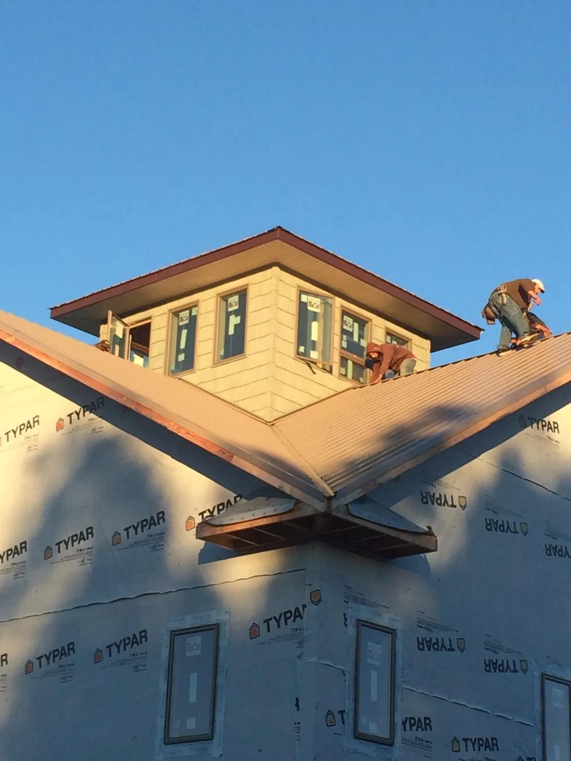 Roofers working around a rooftop cupola on a new metal roof at sunset — Roof Waterproofing in Intervale by Roofing Brothers